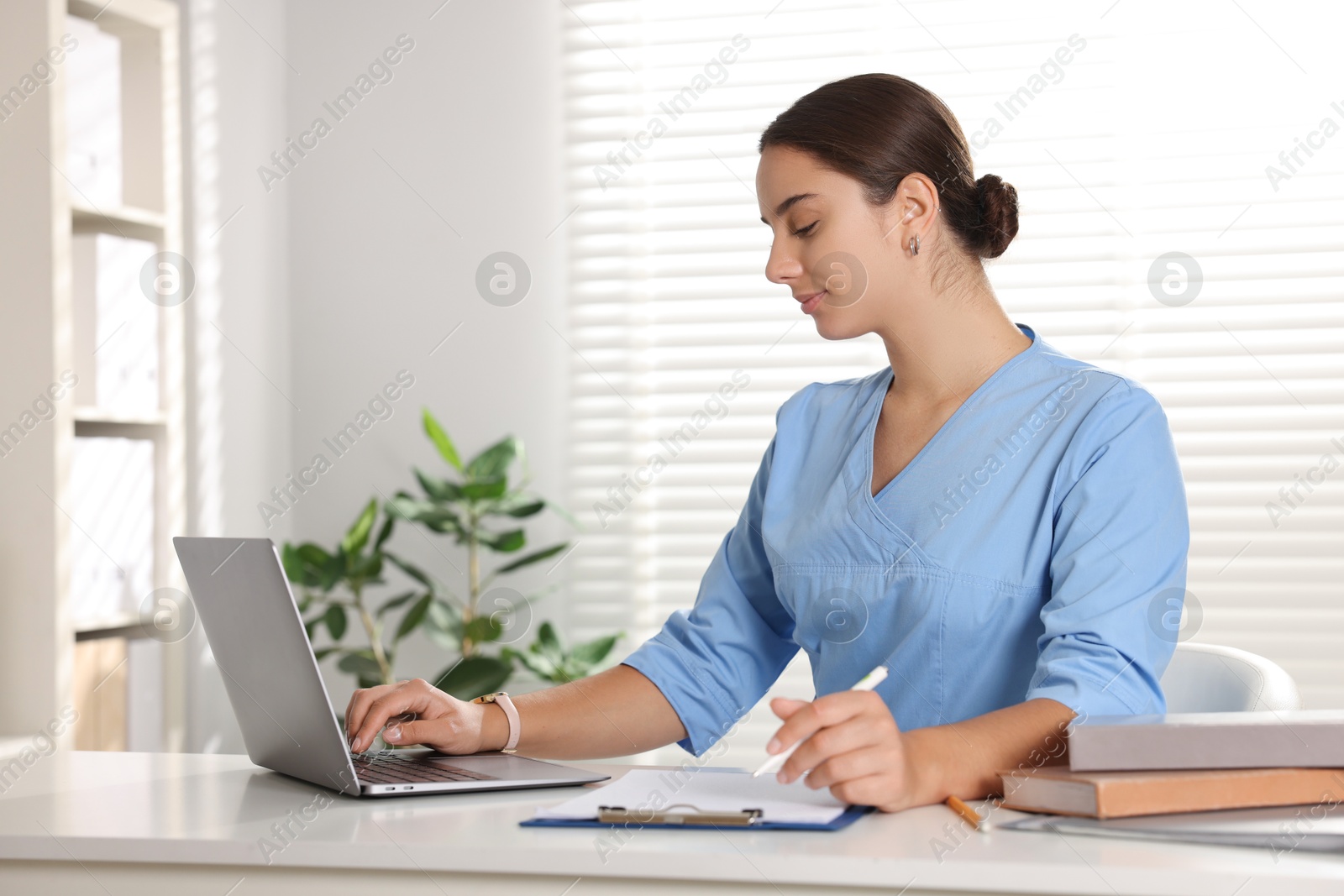 Photo of Medical student studying with laptop at table indoors