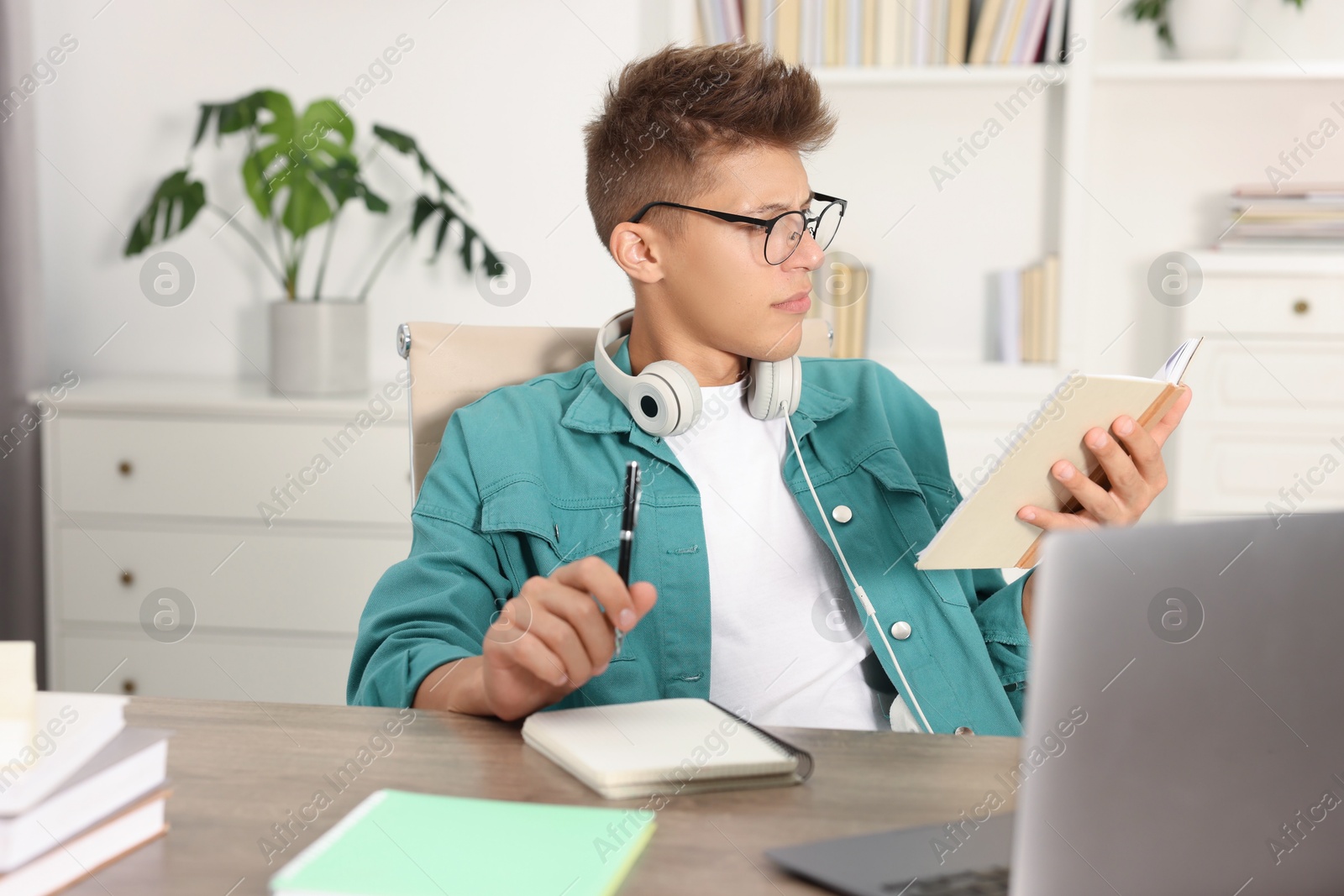 Photo of Student in glasses studying at table indoors