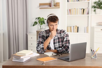 Photo of Student in headphones studying at table indoors