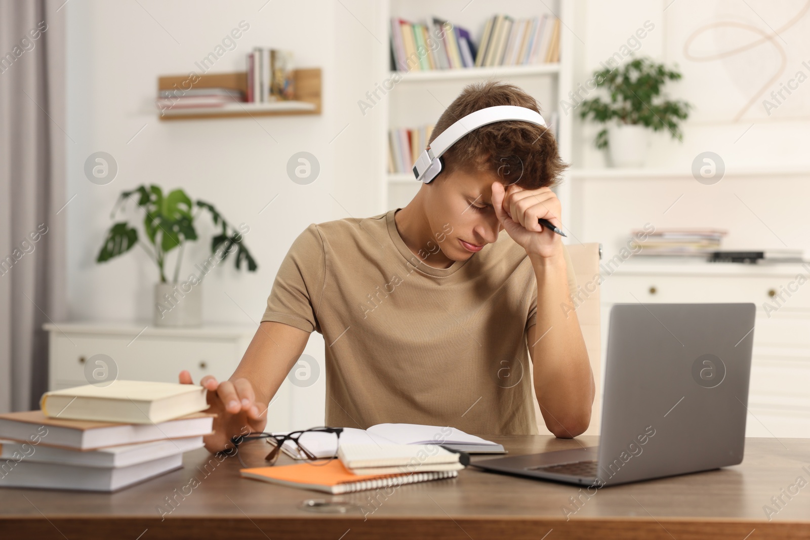 Photo of Student in headphones studying at table indoors