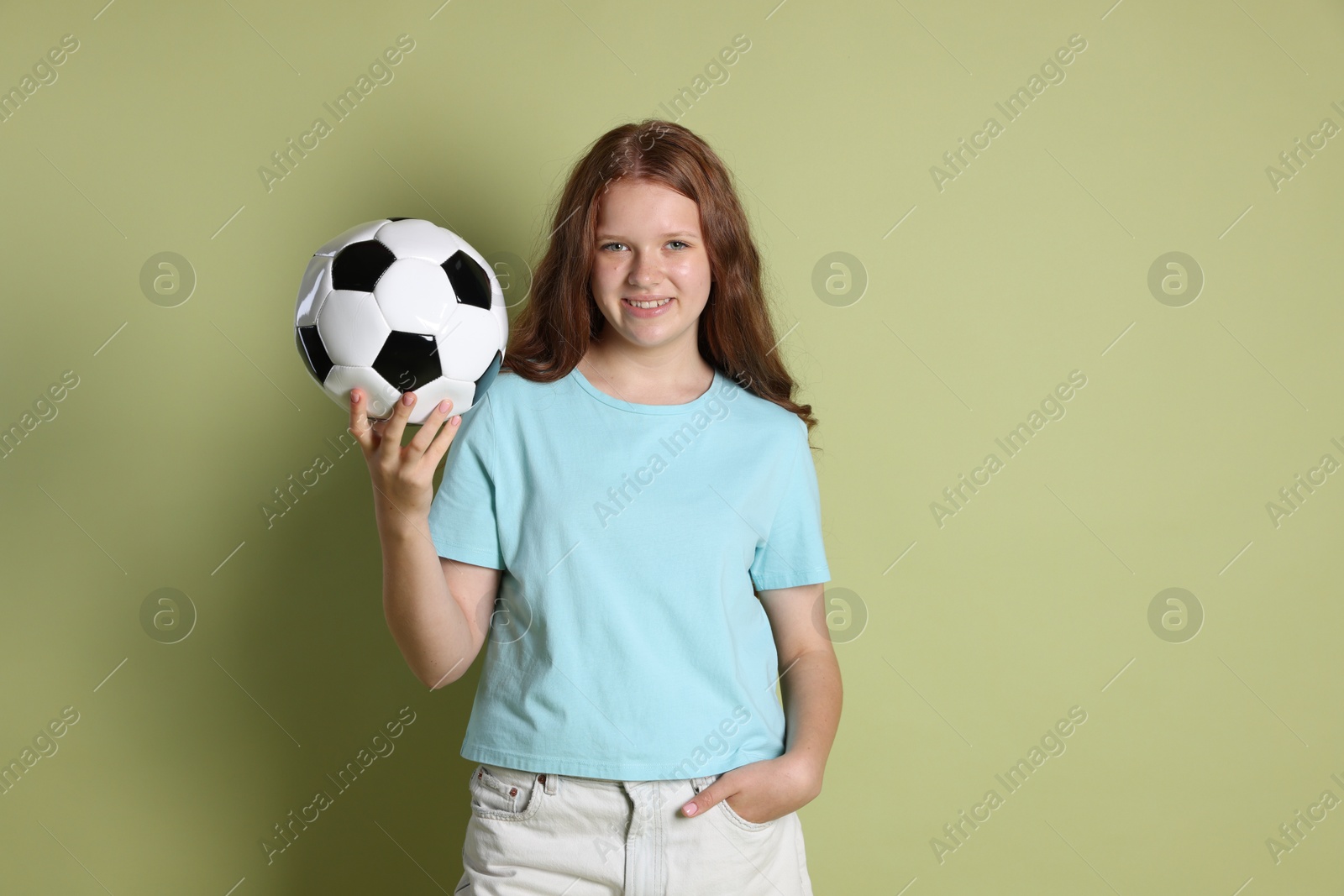 Photo of Smiling teenage girl with soccer ball on green background