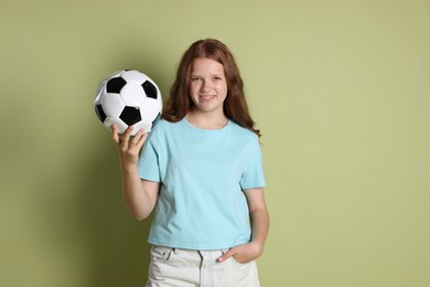 Smiling teenage girl with soccer ball on green background