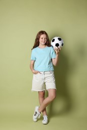 Smiling teenage girl with soccer ball on green background