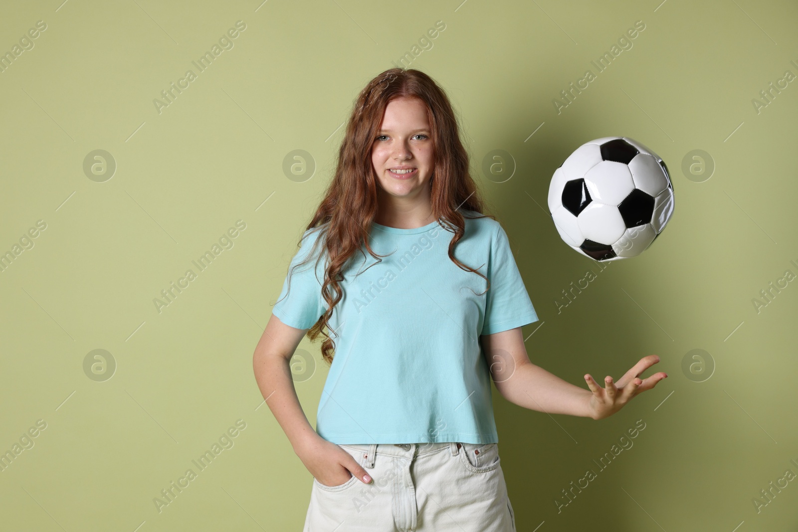 Photo of Smiling teenage girl with soccer ball on green background