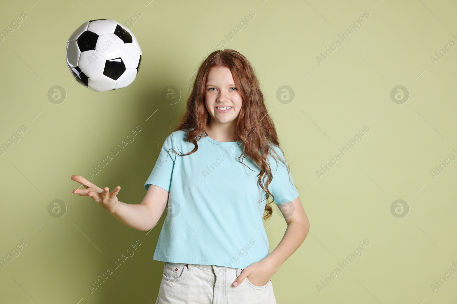 Photo of Smiling teenage girl with soccer ball on green background