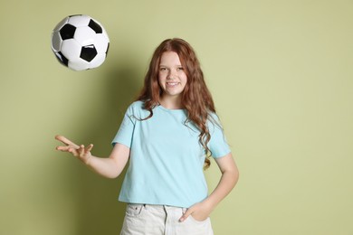 Smiling teenage girl with soccer ball on green background