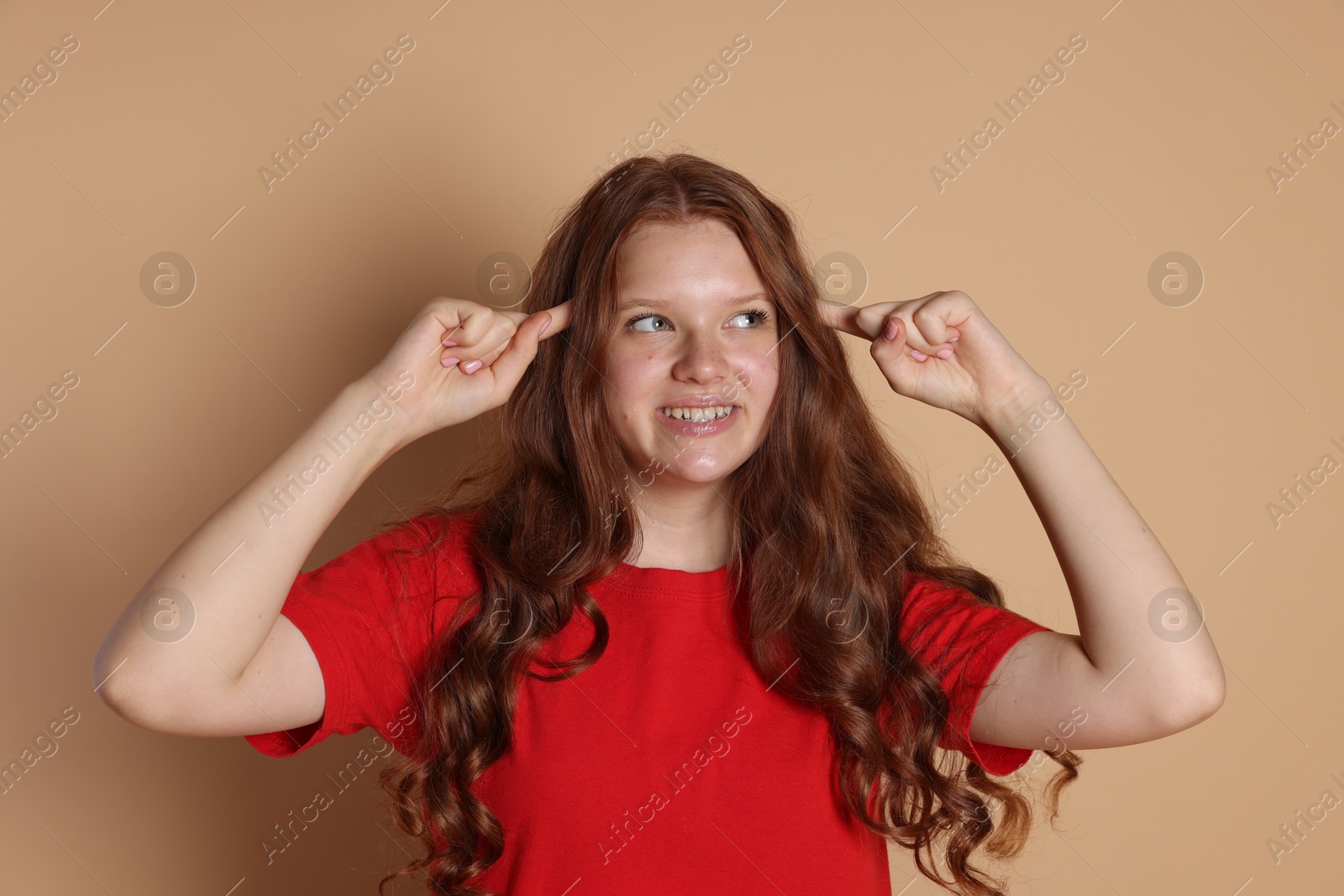 Photo of Smiling teenage girl gesturing on beige background