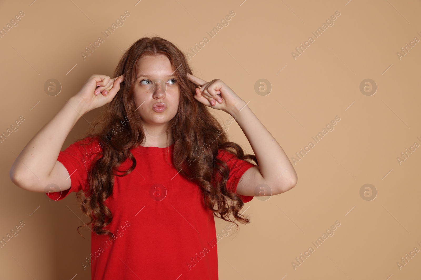 Photo of Cute teenage girl gesturing on beige background. Space for text