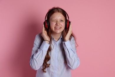 Photo of Smiling teenage girl in headphones listening to music on pink background