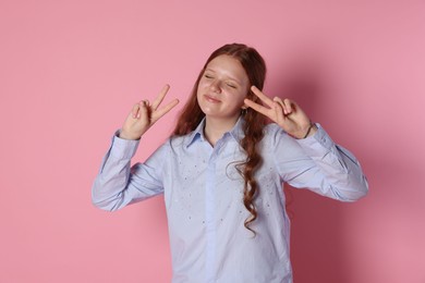 Photo of Cute teenage girl showing peace signs on pink background