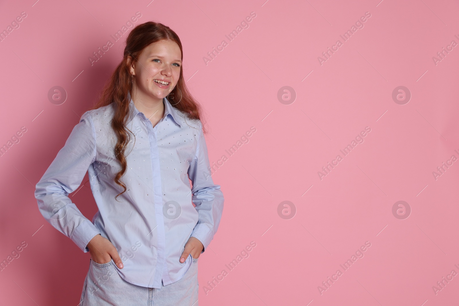 Photo of Happy teenage girl posing on pink background. Space for text