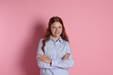 Happy teenage girl with crossed arms on pink background