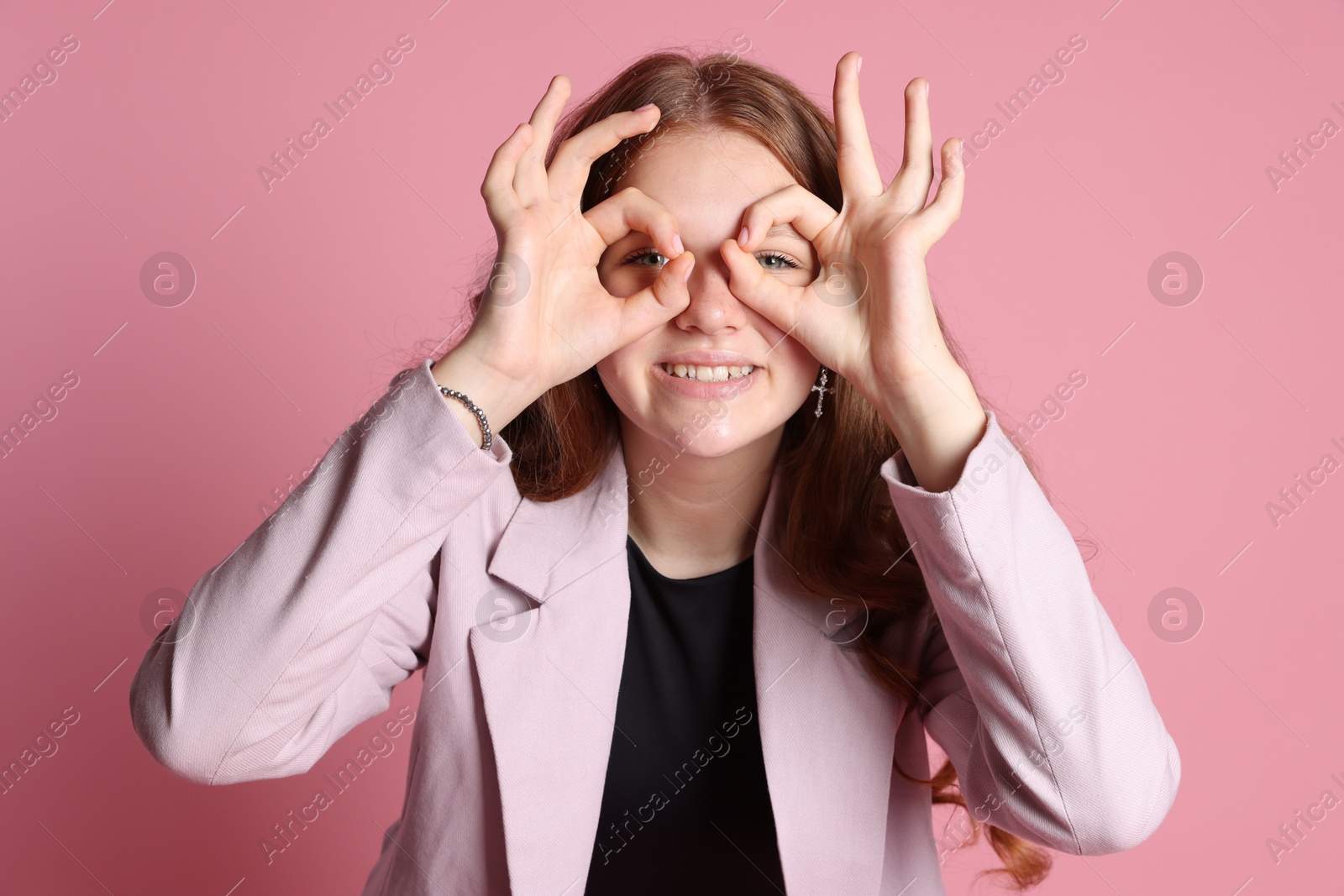 Photo of Smiling teenage girl posing on pink background