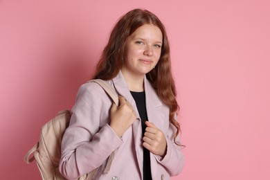 Cute teenage girl with backpack on pink background