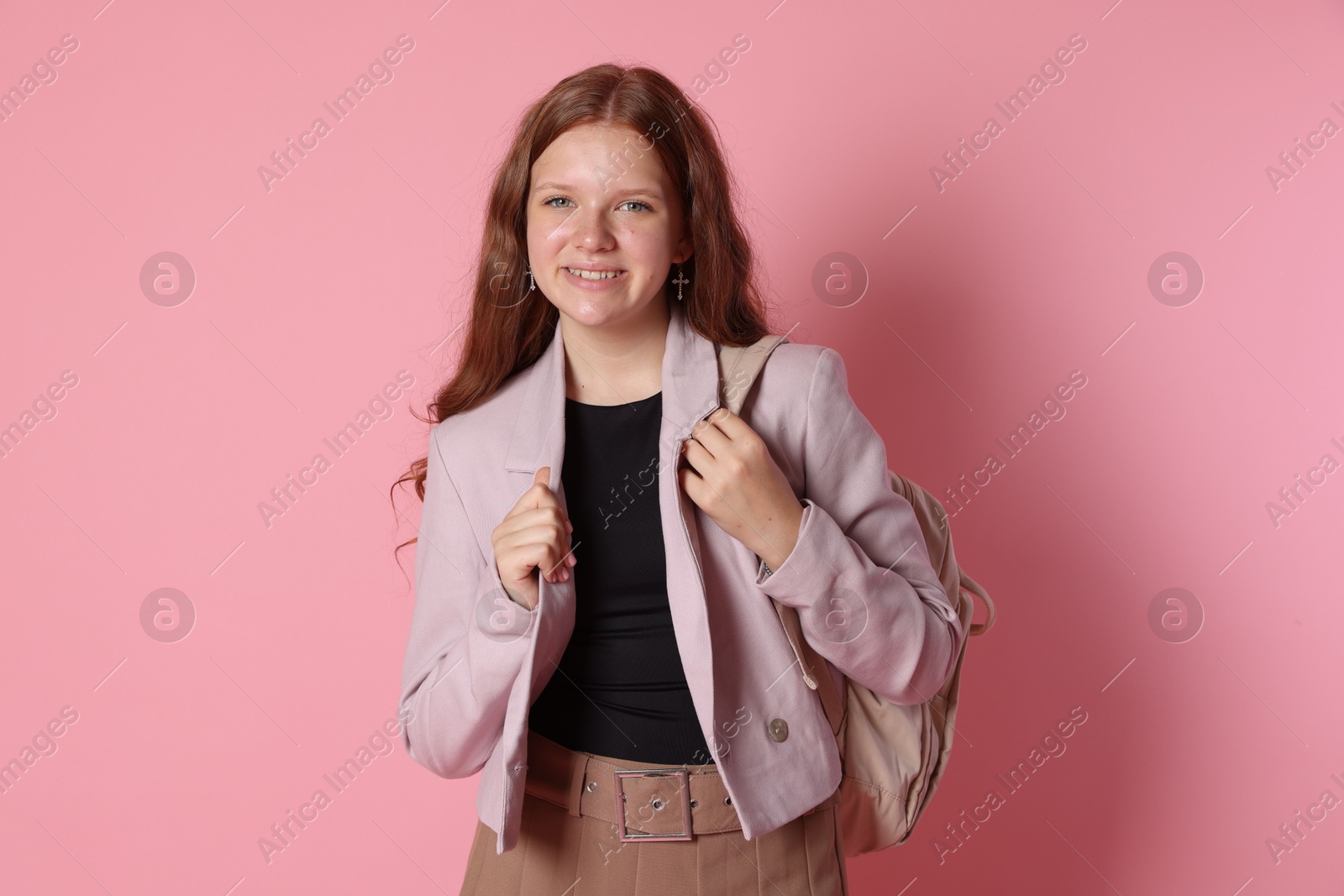 Photo of Smiling teenage girl with backpack on pink background