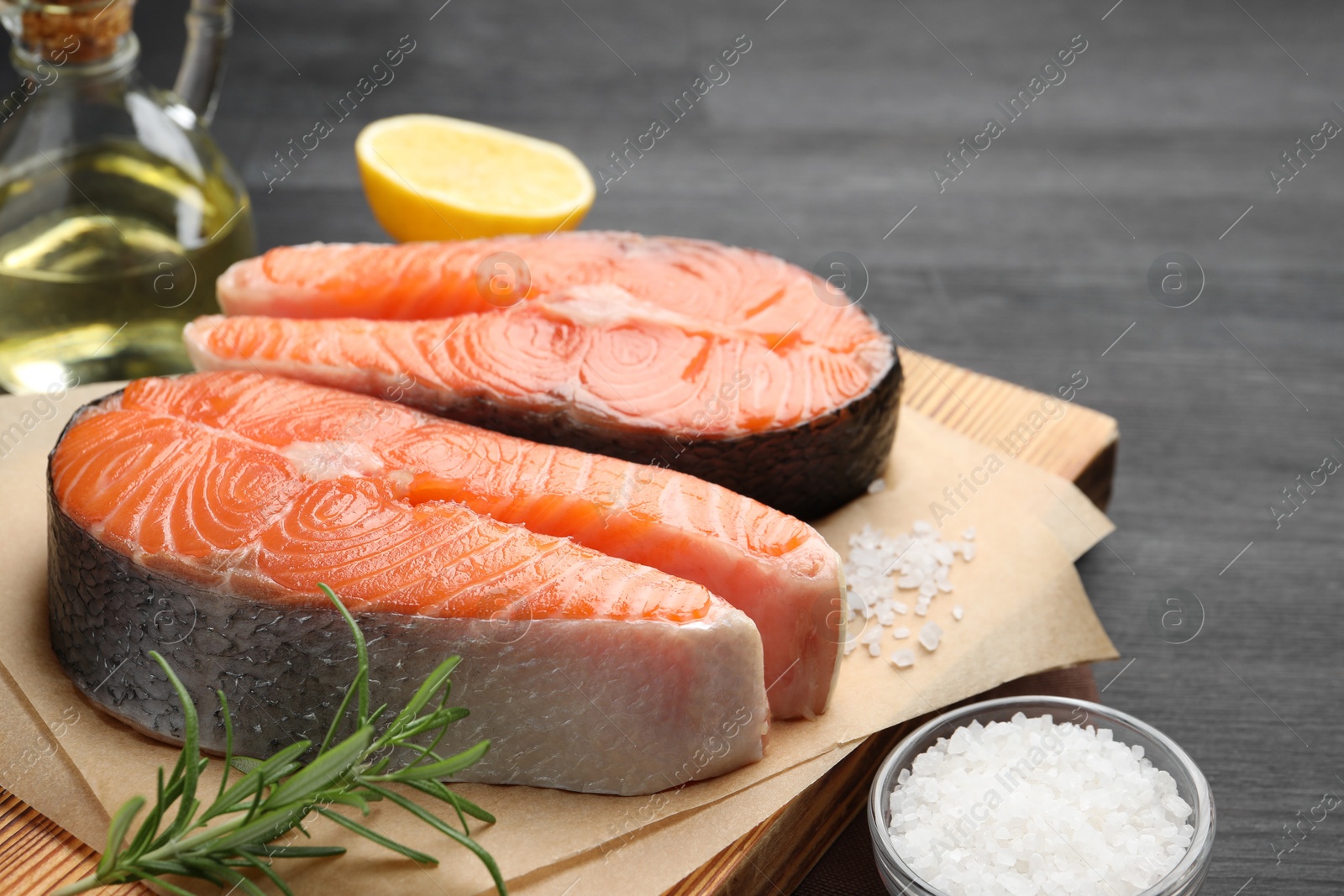 Photo of Fresh raw salmon steaks and spices on black table, closeup