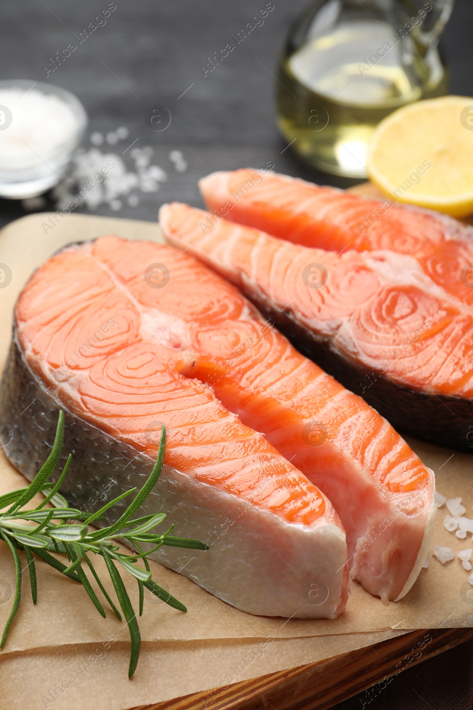 Photo of Fresh raw salmon steaks and spices on black table, closeup