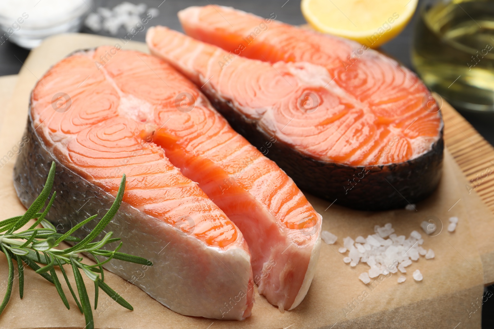 Photo of Fresh raw salmon steaks and spices on black table, closeup