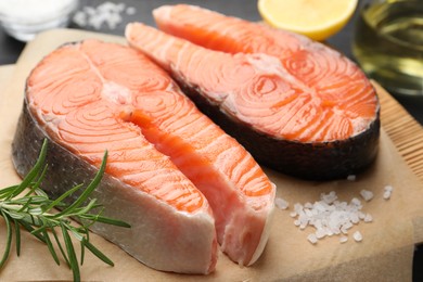 Photo of Fresh raw salmon steaks and spices on black table, closeup