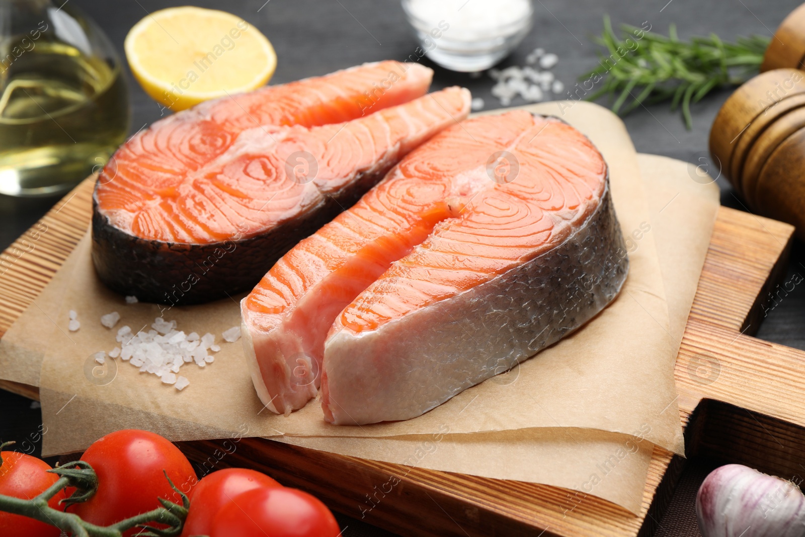 Photo of Fresh raw salmon steaks and spices on black table, closeup