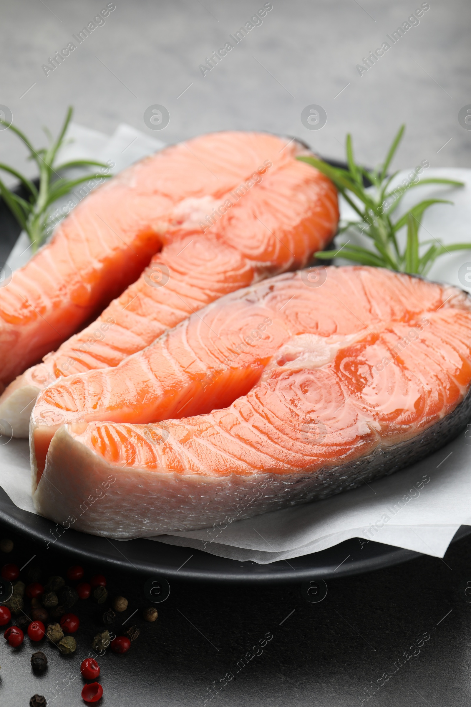 Photo of Fresh raw salmon steaks and spices on grey table, closeup