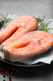 Photo of Fresh raw salmon steaks and spices on grey table, closeup