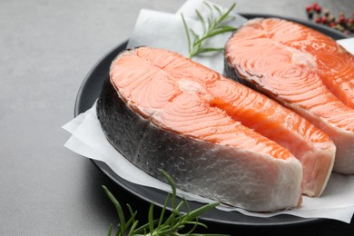 Photo of Fresh raw salmon steaks and spices on grey table, closeup