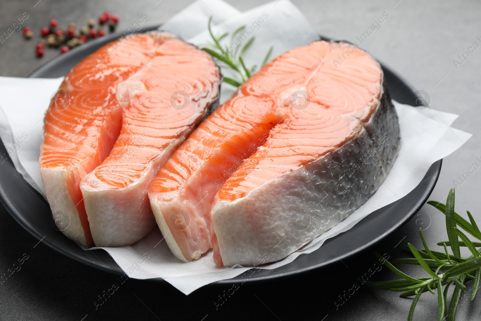 Photo of Fresh raw salmon steaks and spices on grey table, closeup