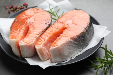 Photo of Fresh raw salmon steaks and spices on grey table, closeup