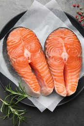 Photo of Fresh raw salmon steaks and spices on grey textured table, top view