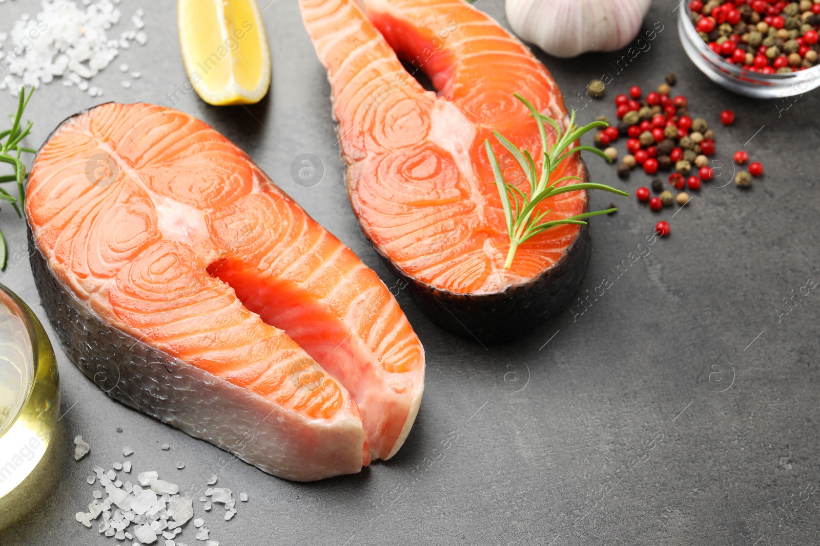 Photo of Fresh raw salmon steaks and spices on grey textured table, closeup