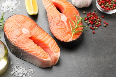 Photo of Fresh raw salmon steaks and spices on grey textured table, closeup