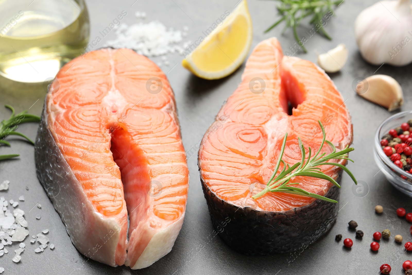 Photo of Fresh raw salmon steaks and spices on grey textured table, closeup