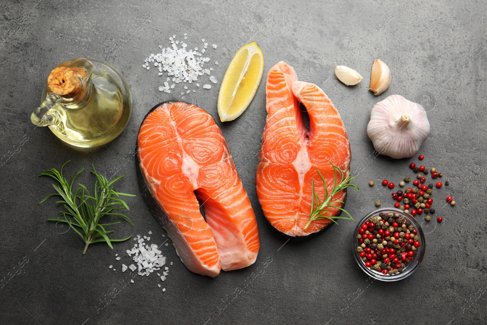 Photo of Fresh raw salmon steaks and spices on grey textured table, flat lay