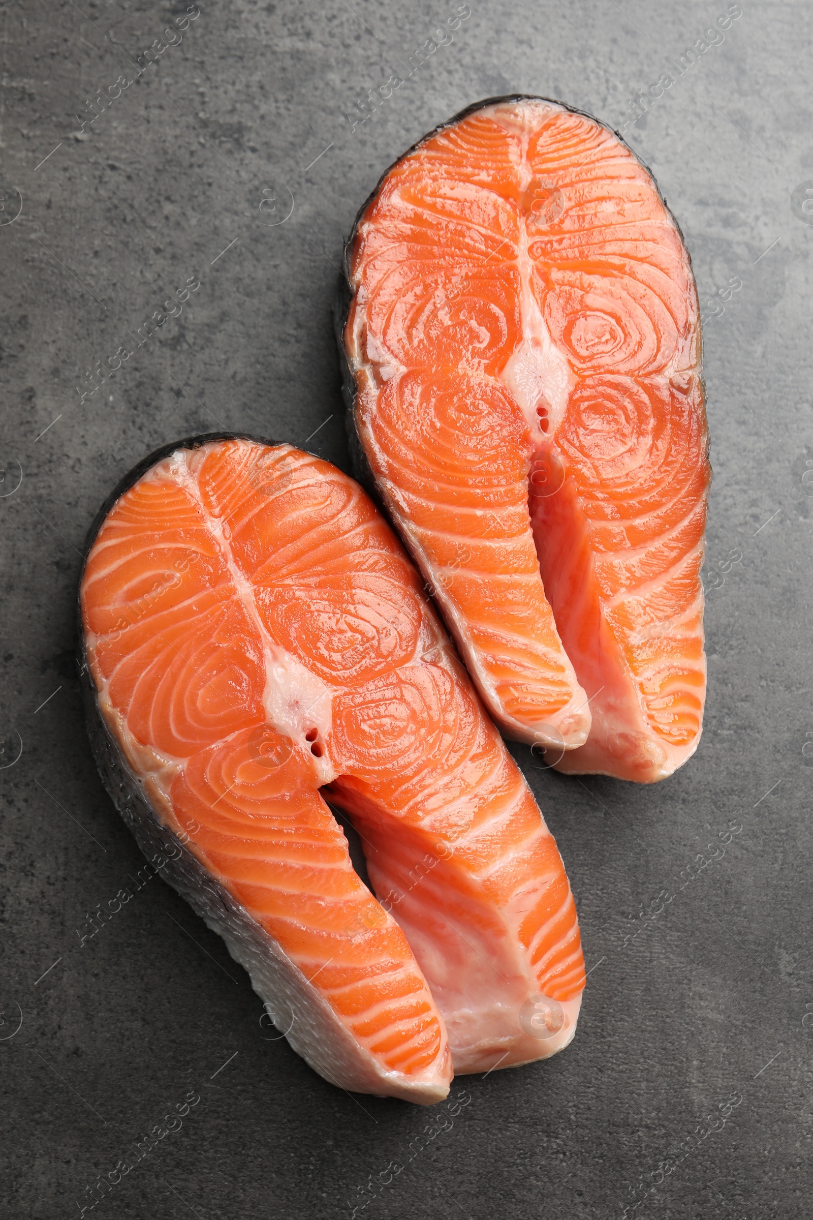 Photo of Fresh raw salmon steaks on grey textured table, top view