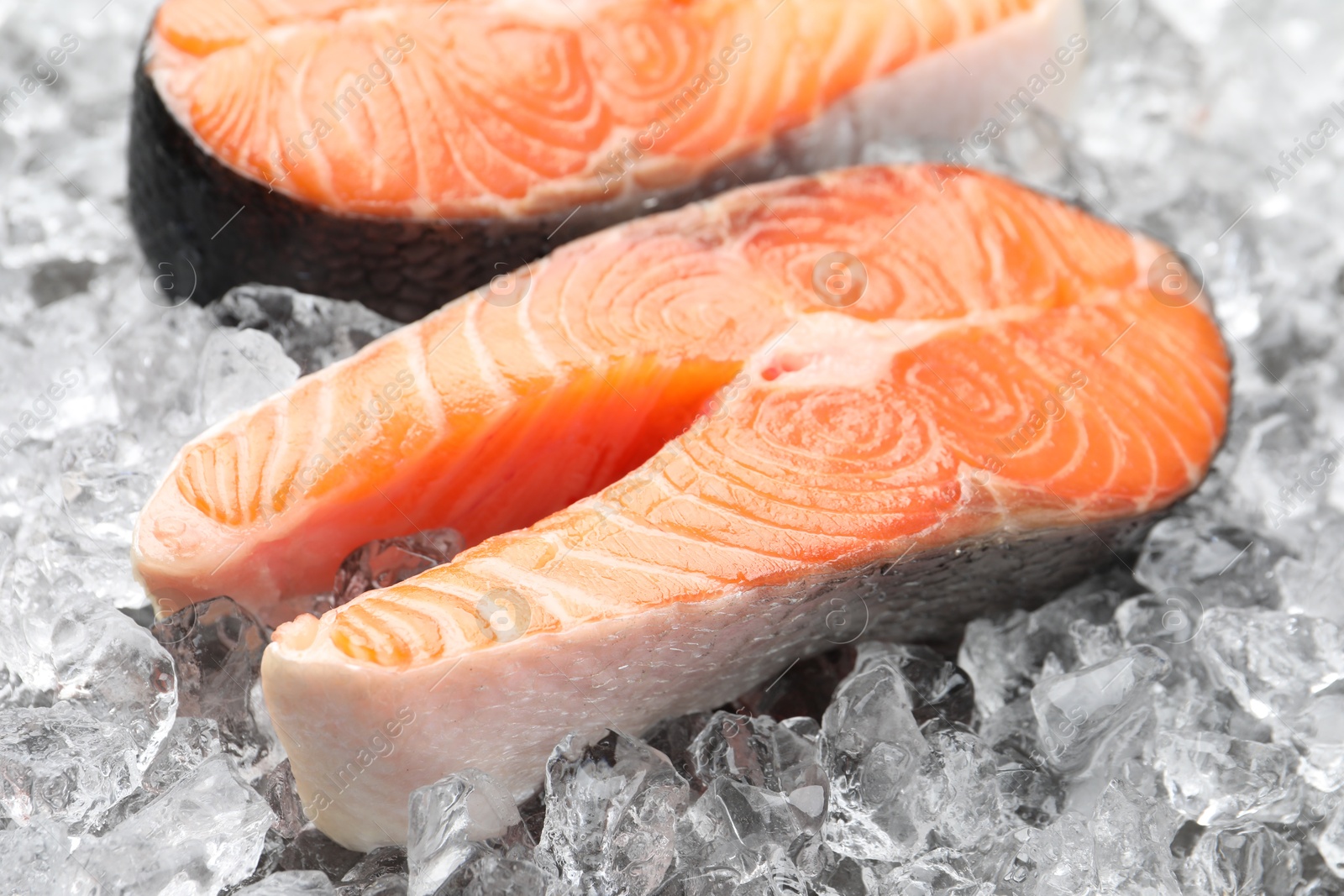 Photo of Fresh raw salmon steaks on ice pieces, closeup