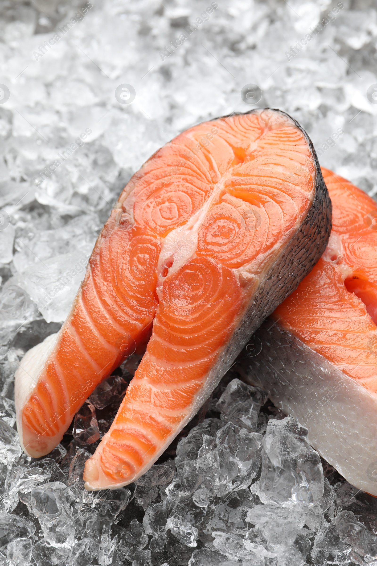 Photo of Fresh raw salmon steaks on ice pieces, closeup