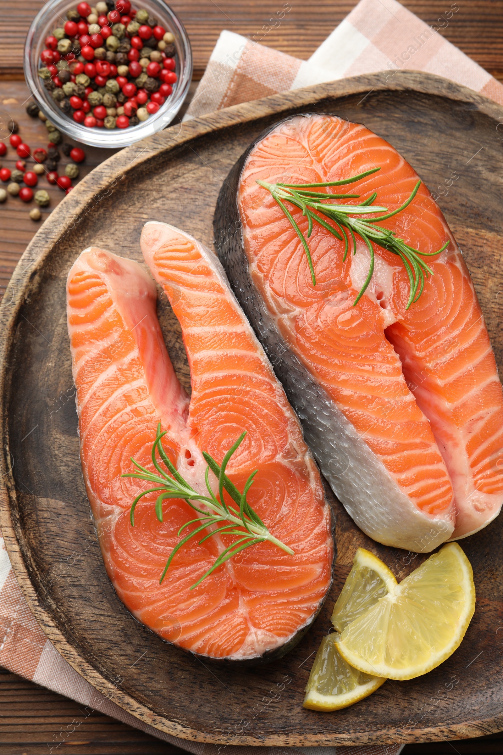 Photo of Fresh raw salmon steaks and spices on wooden table, top view