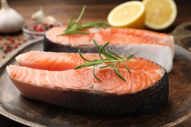 Photo of Fresh raw salmon steaks and rosemary on table, closeup