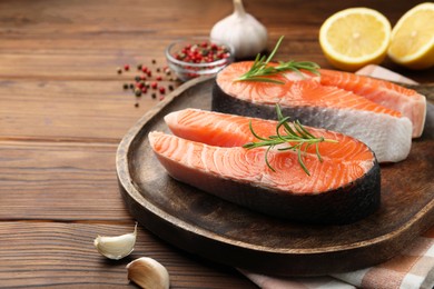 Photo of Fresh raw salmon steaks and spices on wooden table, closeup