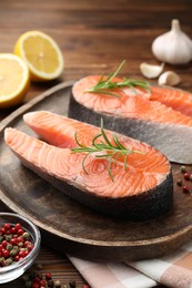 Photo of Fresh raw salmon steaks and spices on wooden table, closeup