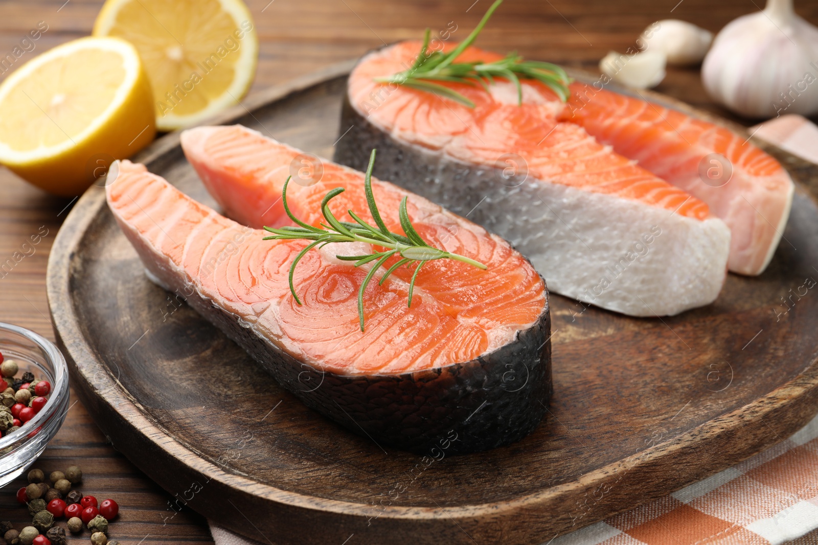 Photo of Fresh raw salmon steaks and spices on wooden table, closeup