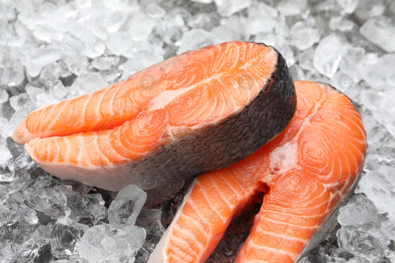 Photo of Fresh raw salmon steaks on ice pieces, closeup