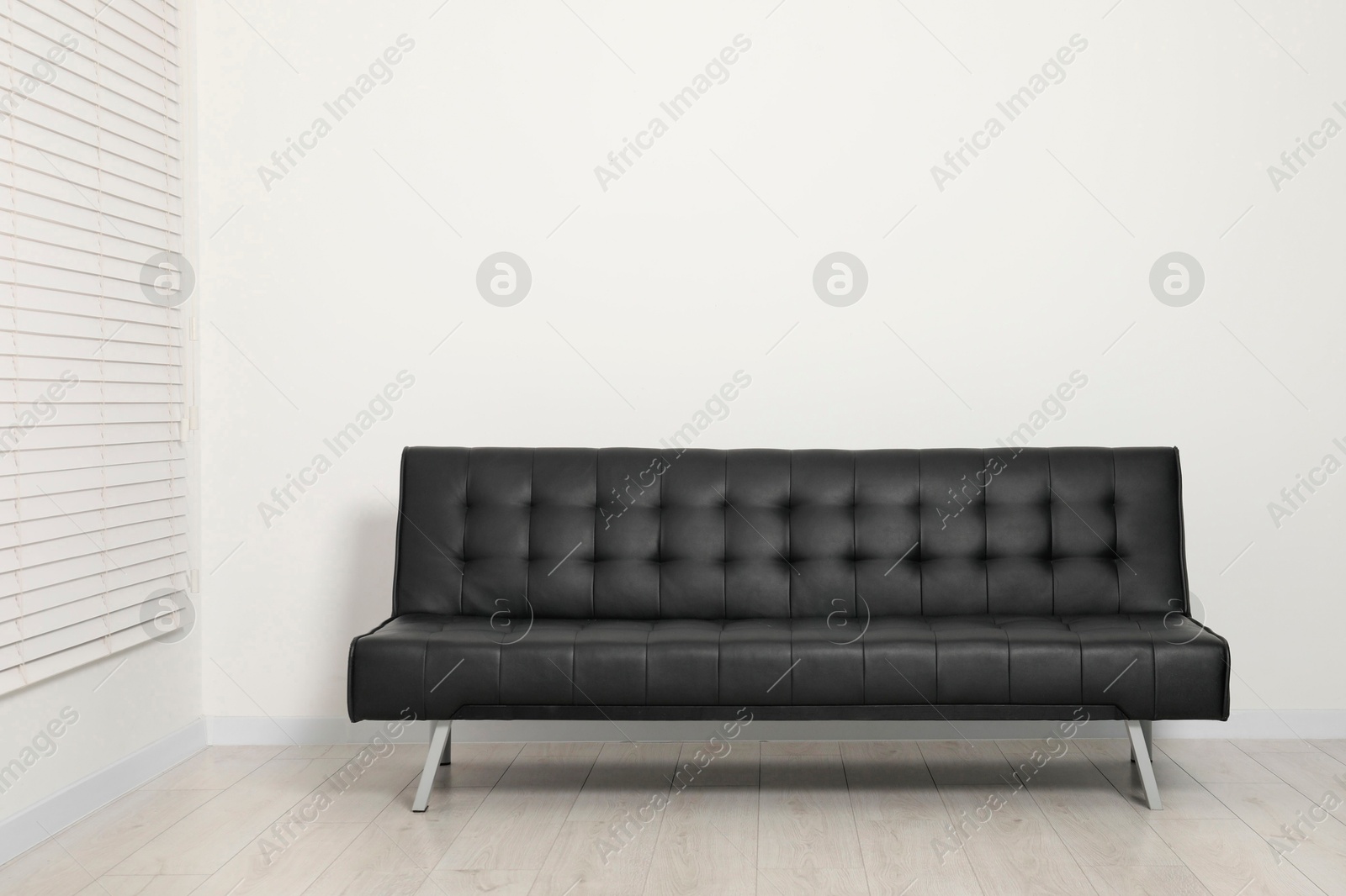 Photo of Comfortable couch near white wall. Interior design