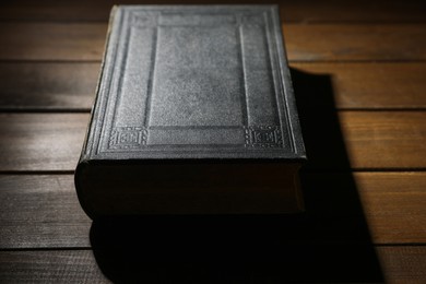 Photo of Closed Bible on wooden table, closeup. Christian faith