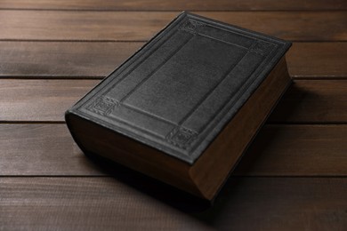 Photo of Closed Bible on wooden table. Christian faith