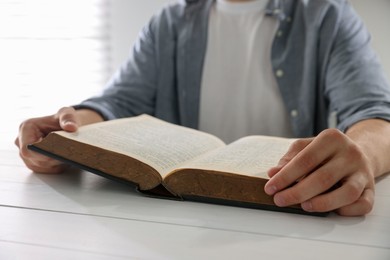 Photo of Man with Bible at white wooden table, closeup