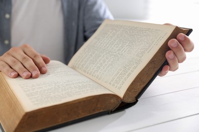 Photo of Man with Bible at white wooden table, closeup