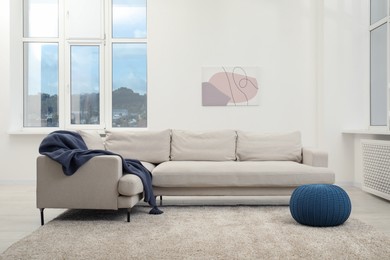 Photo of Stylish room interior with comfortable sofa and pouf