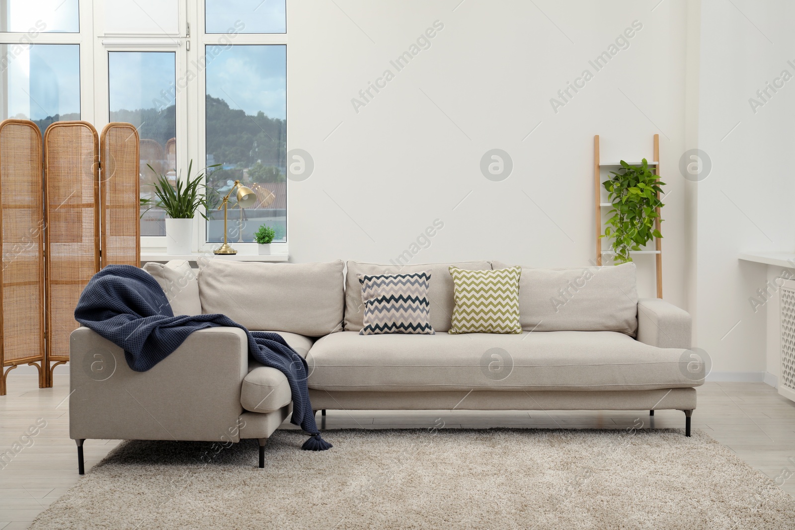 Photo of Stylish room interior with comfortable sofa and houseplants